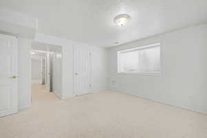 Bright room featuring light-colored carpeting, a window with blinds, and multiple white paneled doors with brass-finish hardware