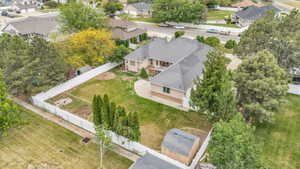 Expansive backyard with a manicured lawn, established trees, and a white perimeter fence