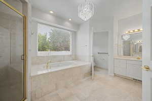 Spacious bathroom featuring a built-in soaking tub with gold-finish fixtures, a separate glass-enclosed shower with gold-finish trim, and a double vanity with a large mirror