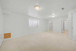 Spacious room featuring light-colored carpeting, white painted walls, and a window with horizontal blinds