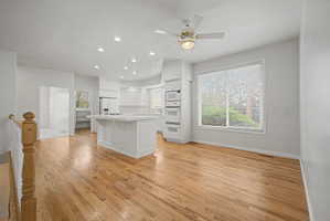 Open-concept kitchen and living area featuring wood-finish flooring, recessed lighting, and a ceiling fan