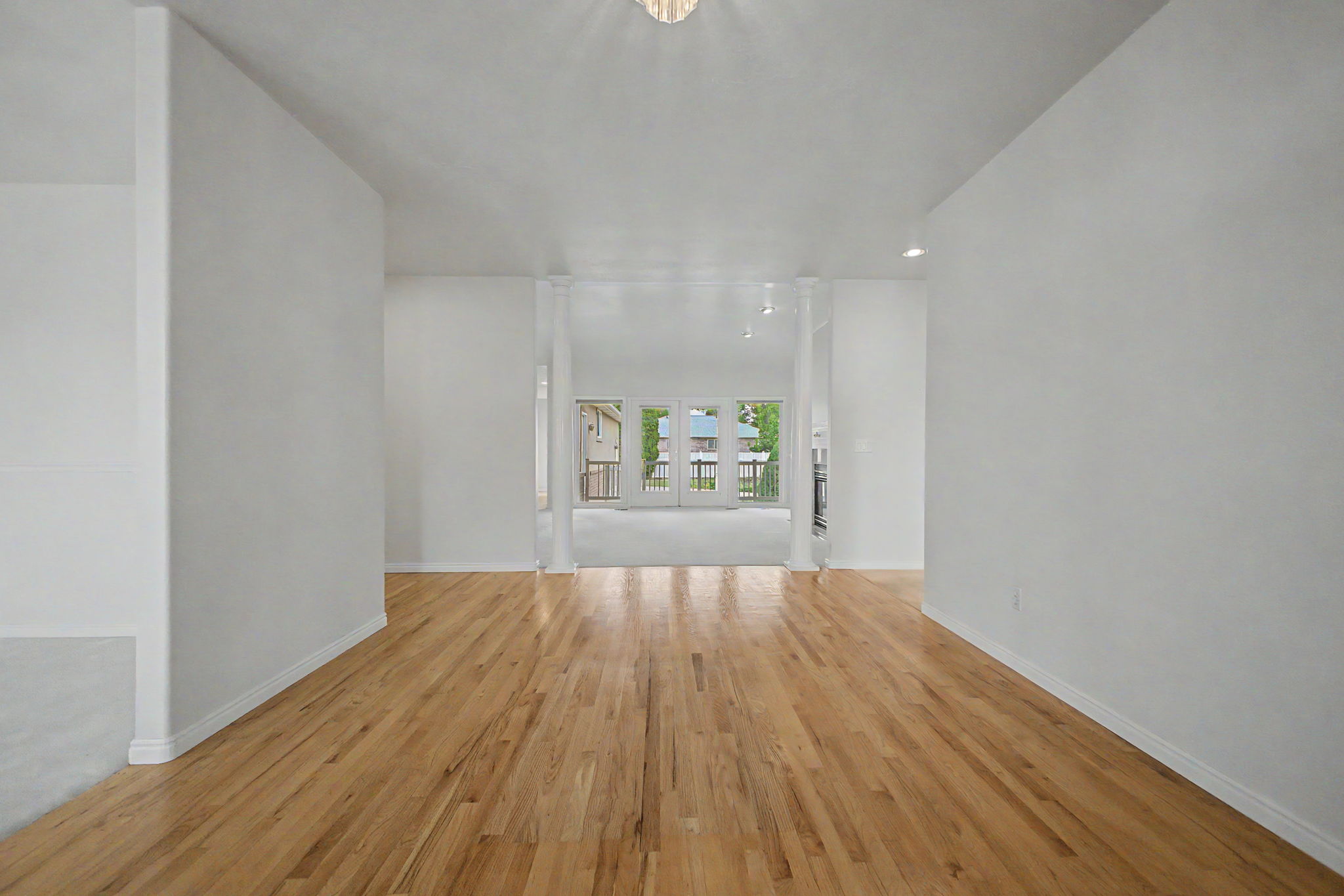 Light wood-finish flooring extending through an open interior with white walls