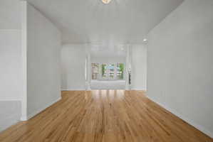 Light wood-finish flooring extending through an open interior with white walls