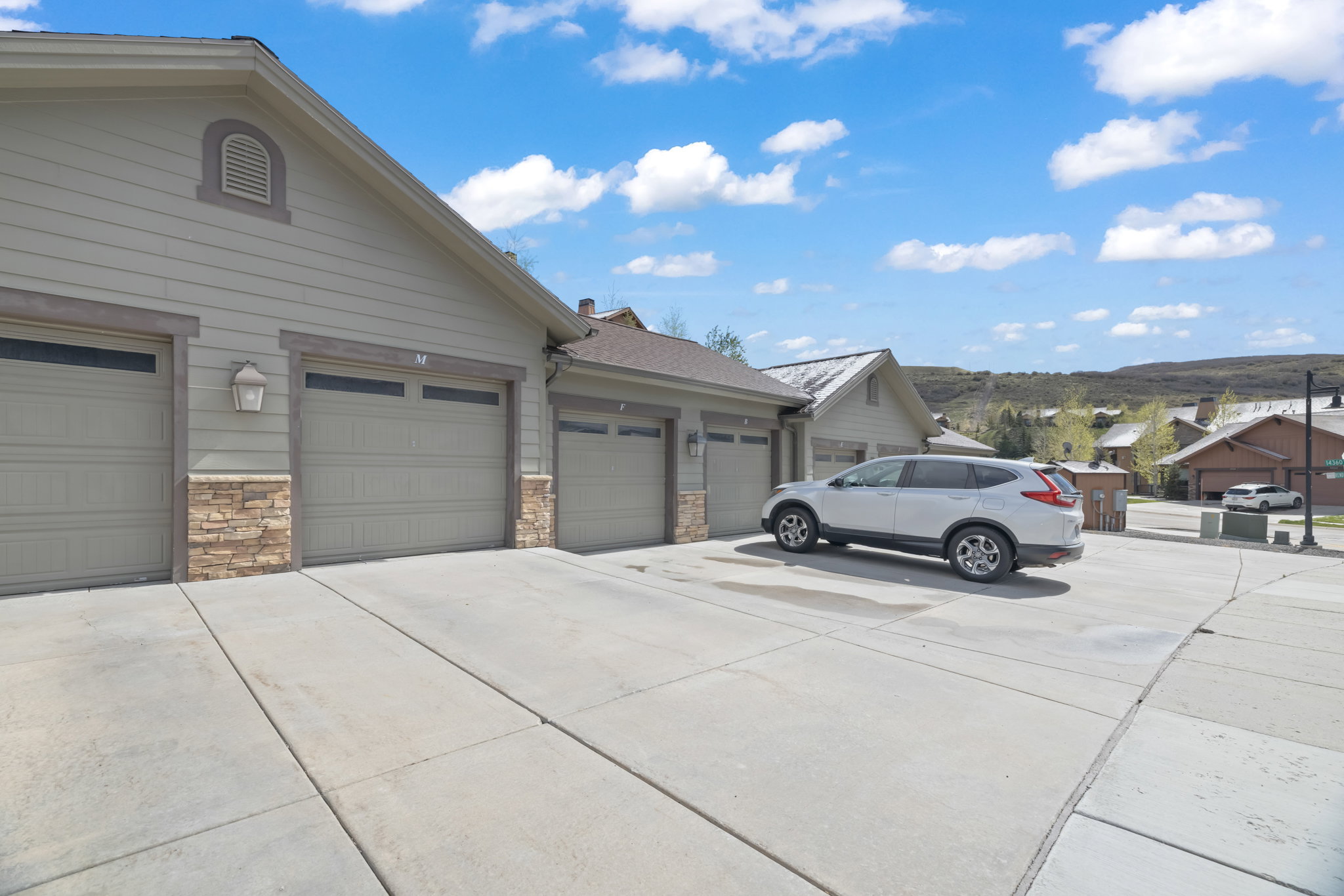 Three garage doors featuring integrated windows and stone veneer accents