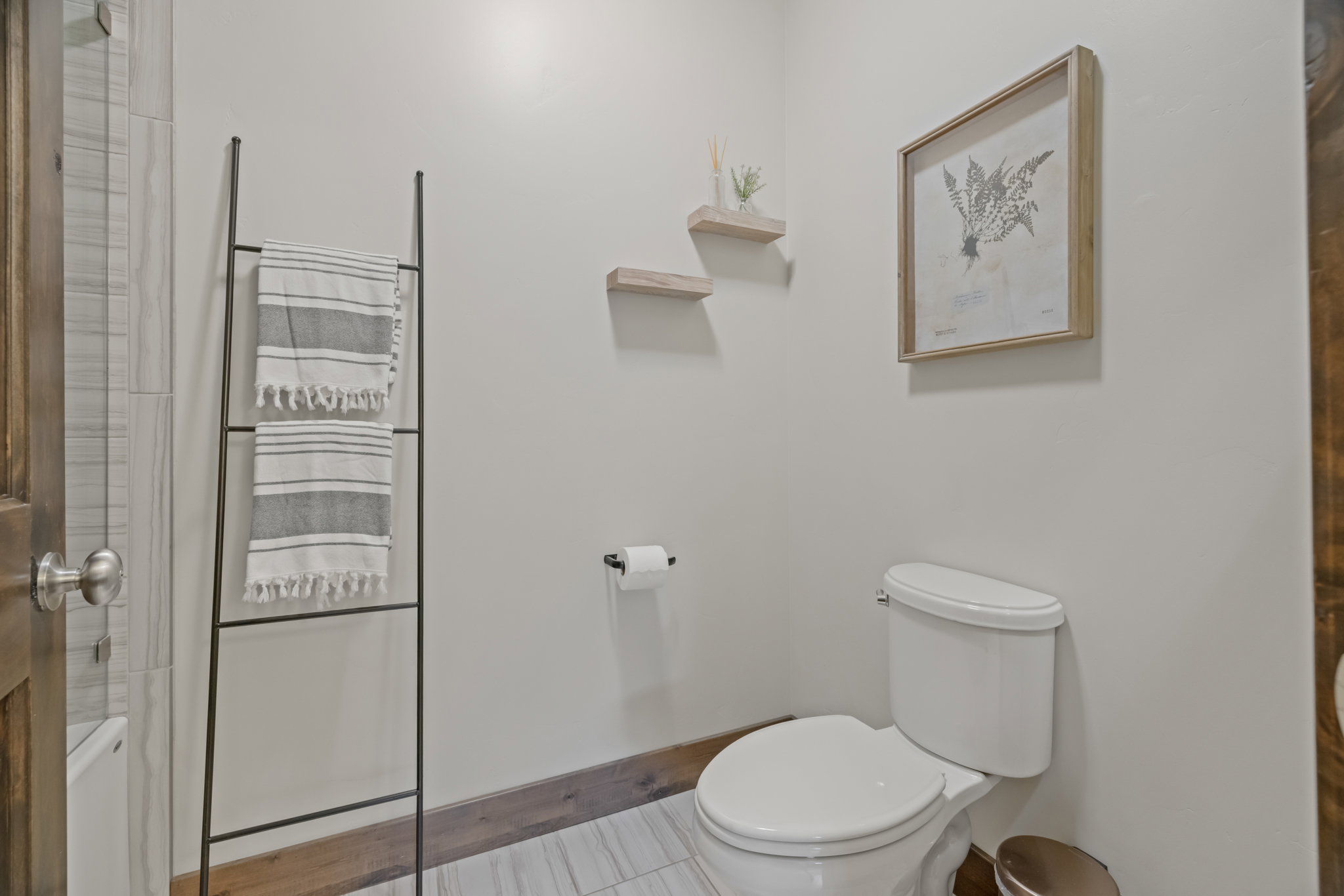Powder room featuring a white toilet, light gray wall paint, and wood-finish baseboards