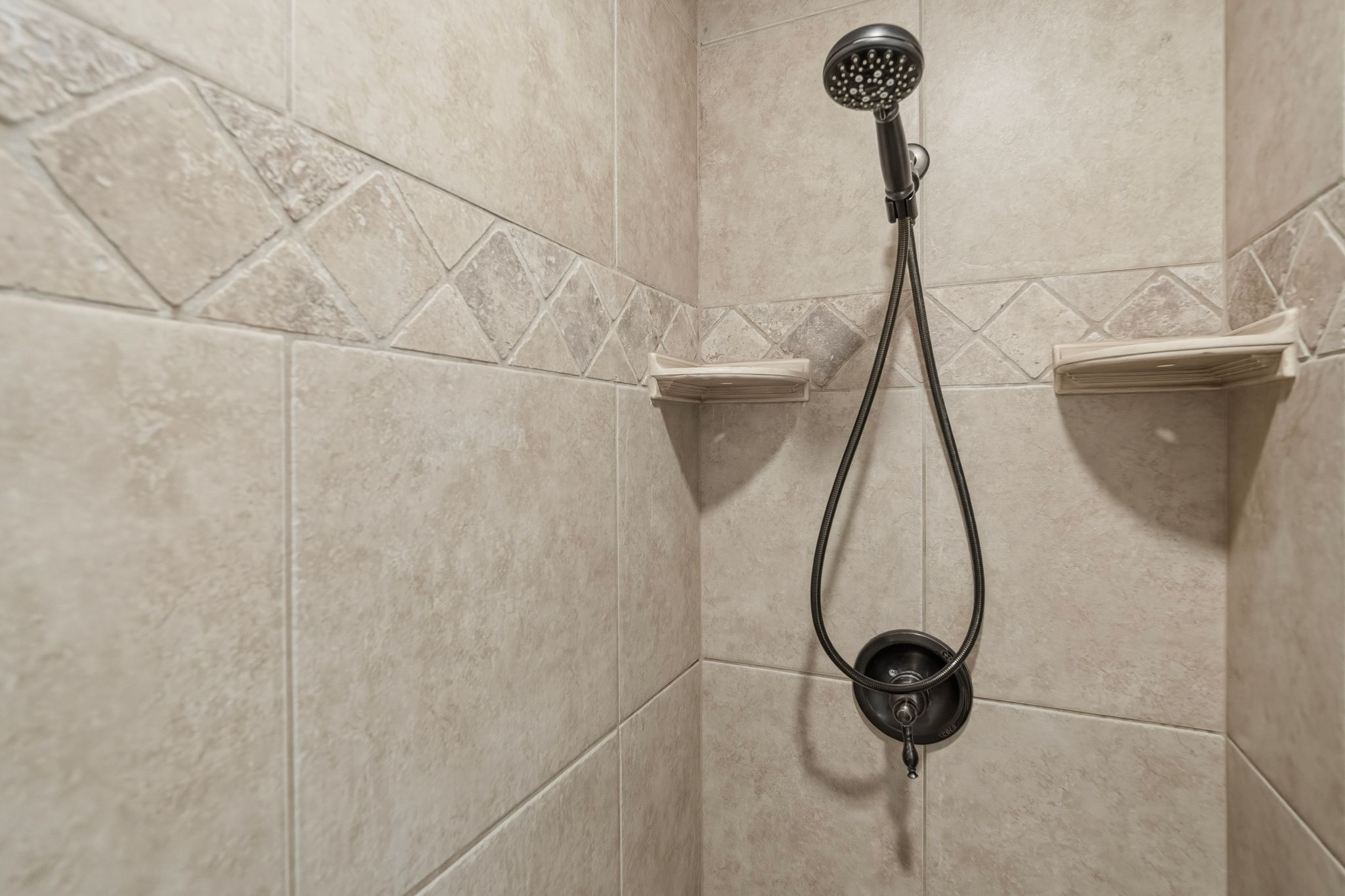 ADU tiled shower surround featuring a decorative accent band