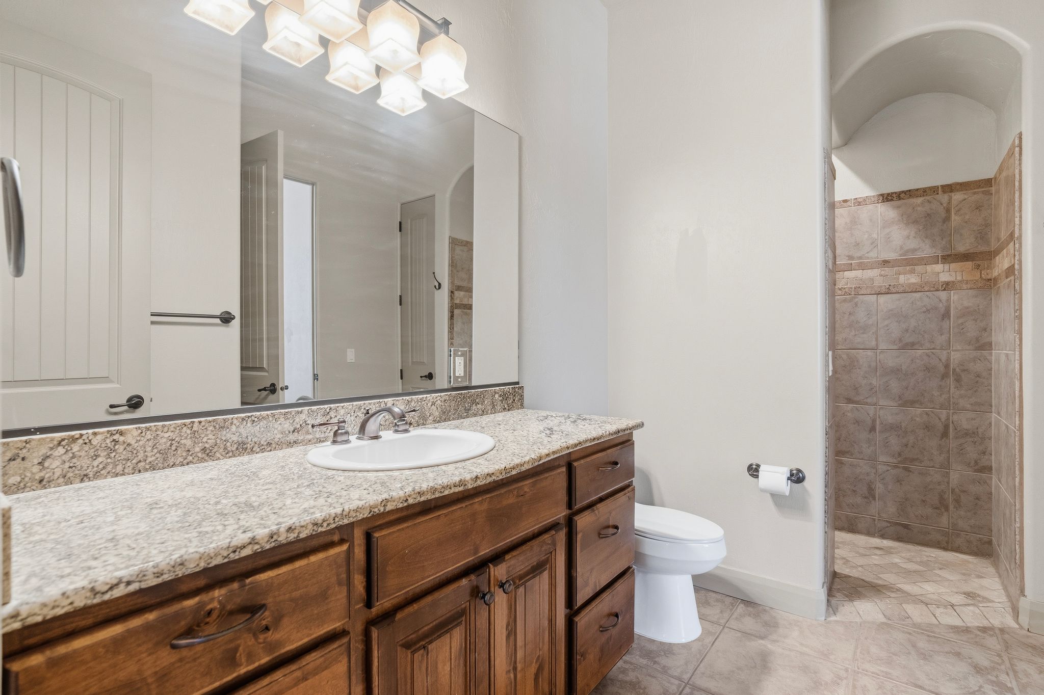 Spacious vanity featuring an undermount sink, granite-style countertop, and wood-finish cabinetry