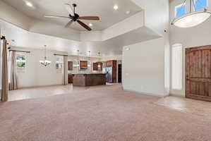 Expansive open-concept living space featuring a tray ceiling, recessed lighting, and a prominent ceiling fan