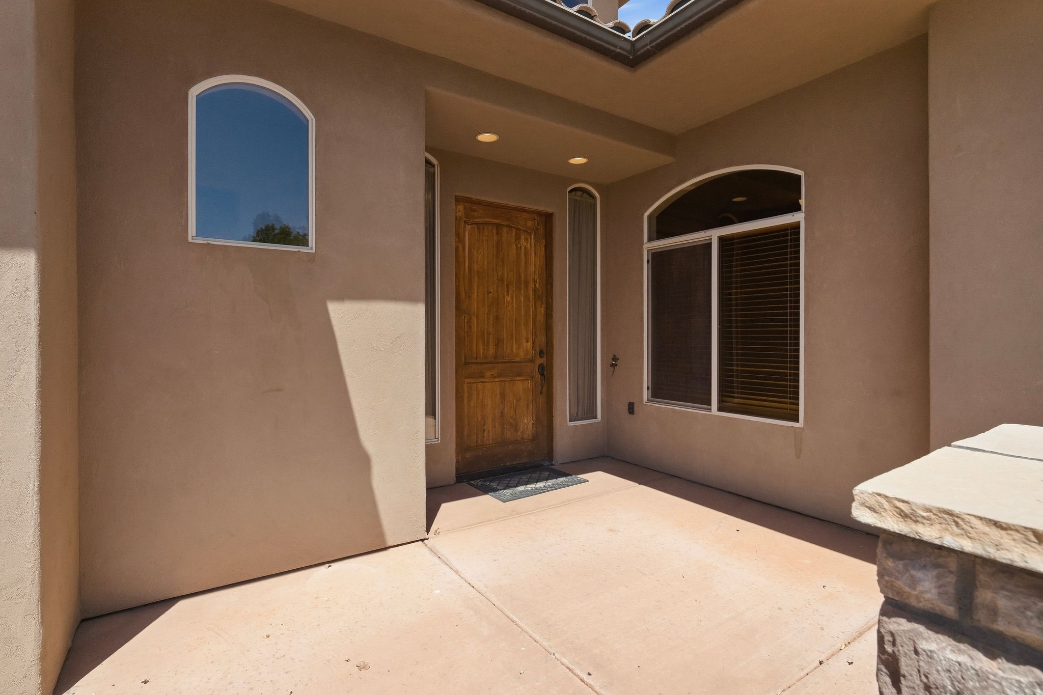 Stucco exterior featuring an arched window, a solid wood entry door, and a skylight