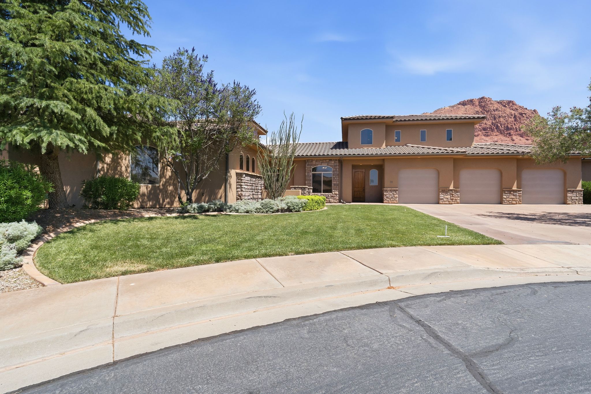 Mediterranean-style exterior featuring a stucco finish, stone accents, and a tile roof