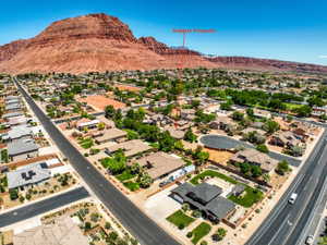 Aerial perspective showcasing the subject property within a residential neighborhood framed by distant red rock formations and a clear sky.
