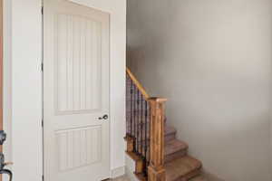 ADU entrance, arched interior door with vertical paneling and matte black hardware, complementing the carpeted staircase with wood newel post and wrought iron balusters