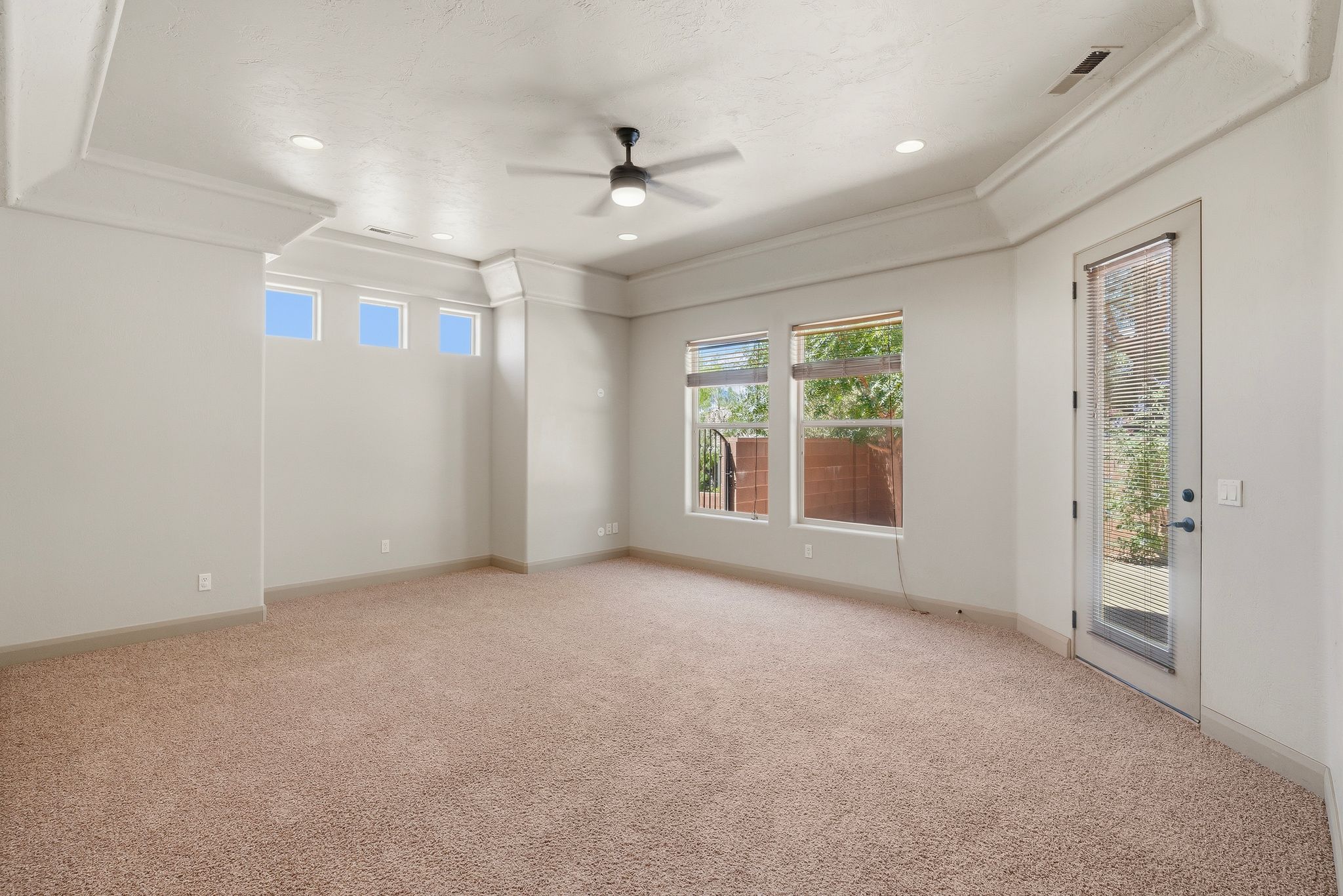 Primary suite, spacious room featuring tray ceiling details, recessed lighting, and a ceiling fan