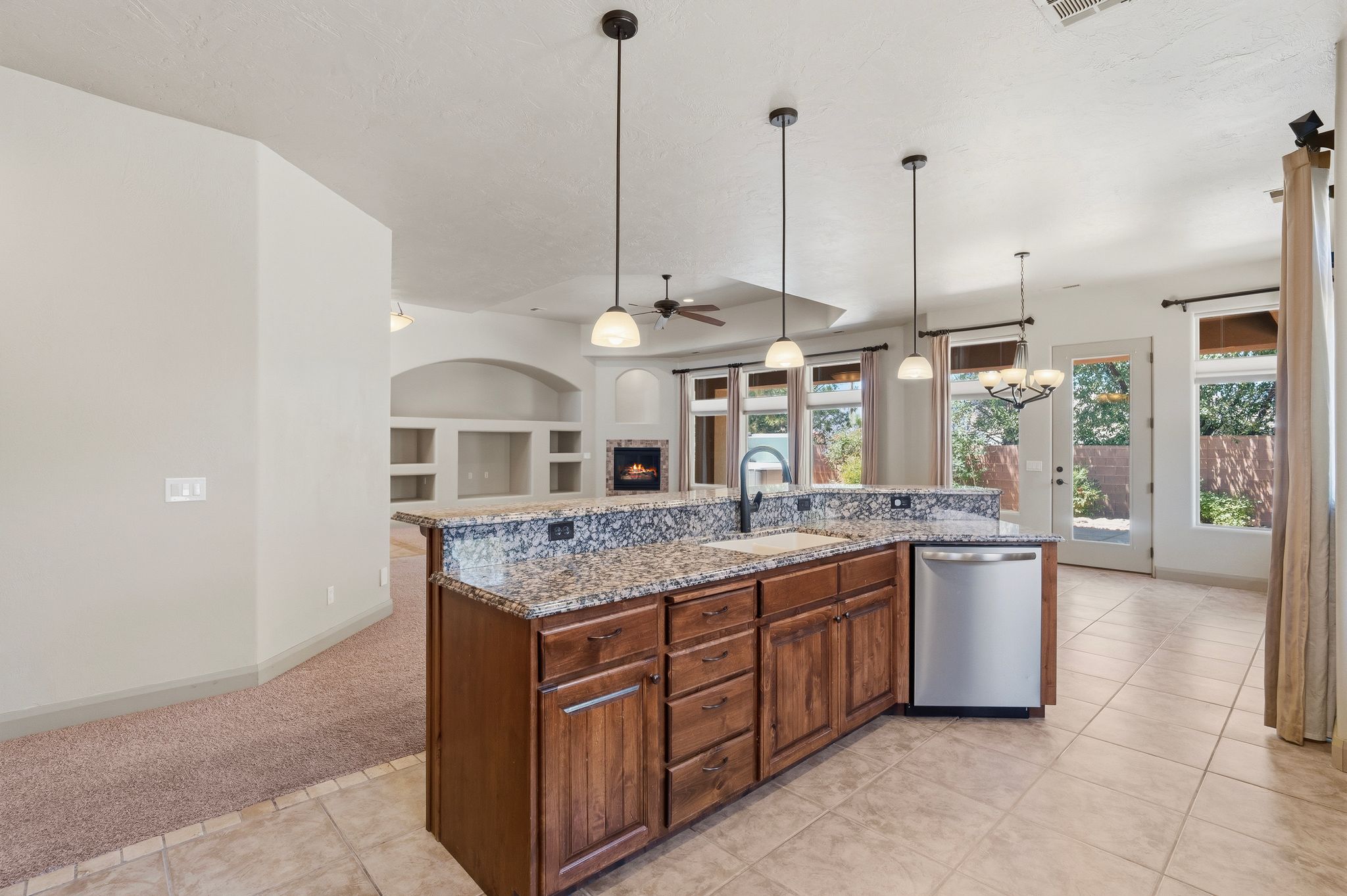 Kitchen island featuring granite-style countertops, wood cabinetry, and a stainless steel dishwasher