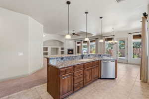 Kitchen island featuring granite-style countertops, wood cabinetry, and a stainless steel dishwasher