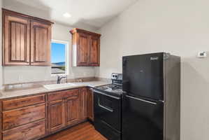 ADU kitchen featuring wood-finish cabinetry, speckled countertops, and a white sink with a black faucet