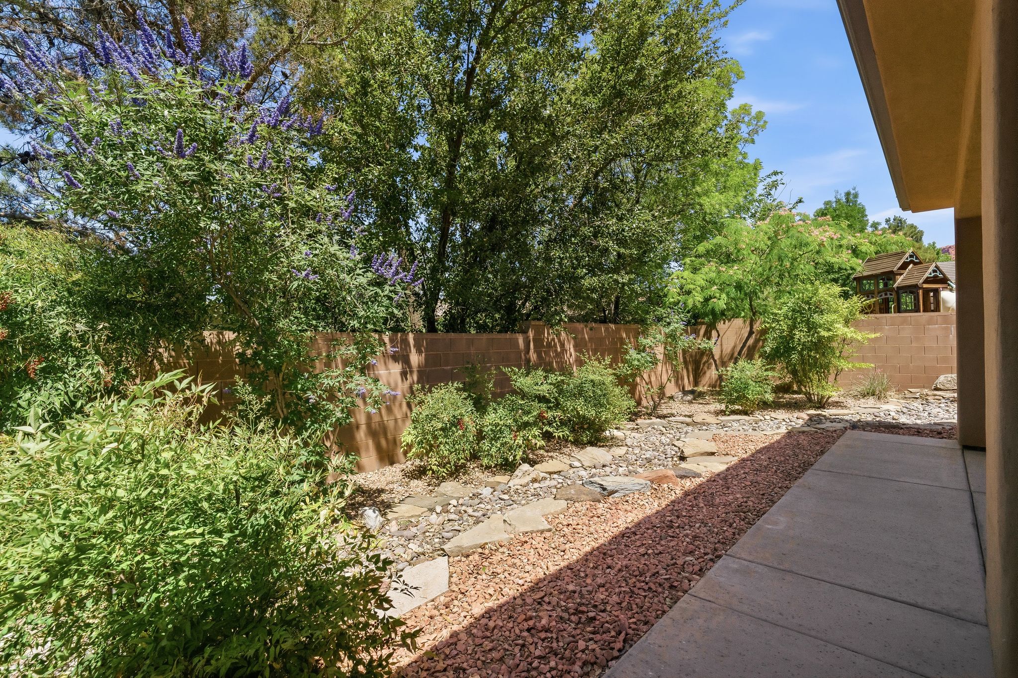 Private backyard featuring a concrete patio, surrounding rock landscaping, and a block fence