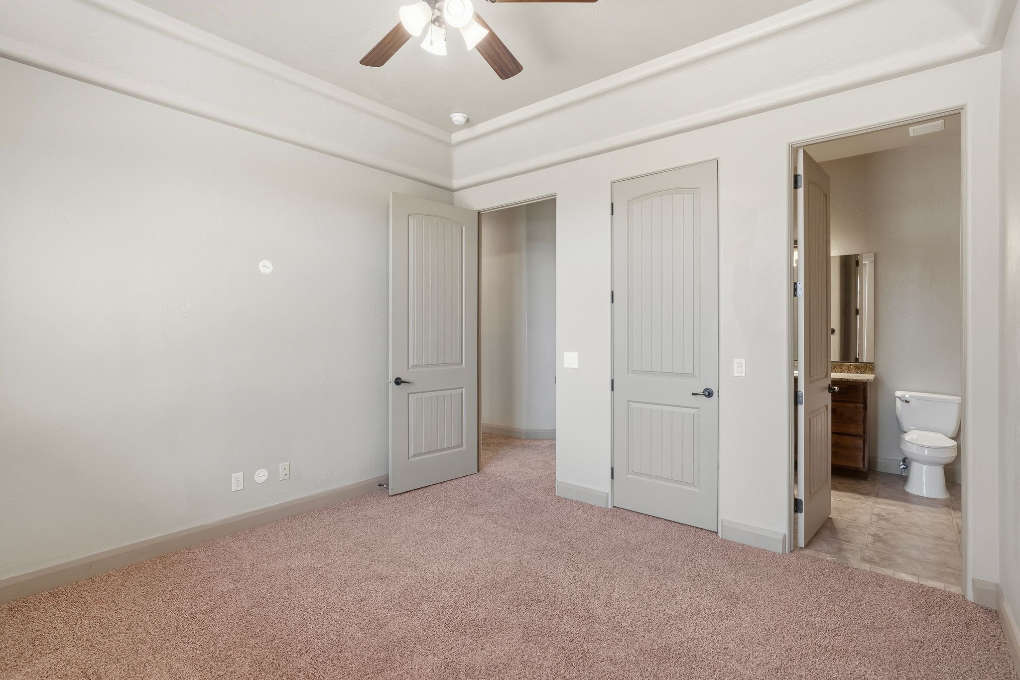 Bedroom 2: Carpeted room featuring a tray ceiling with a ceiling fan