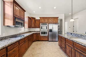 Kitchen featuring wood-finish cabinetry, granite countertops, stainless steel appliances, and tile flooring