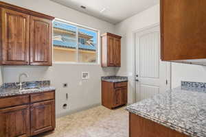 Utility room featuring wood-finish cabinetry, speckled stone countertops, and a single-basin sink with a gooseneck faucet