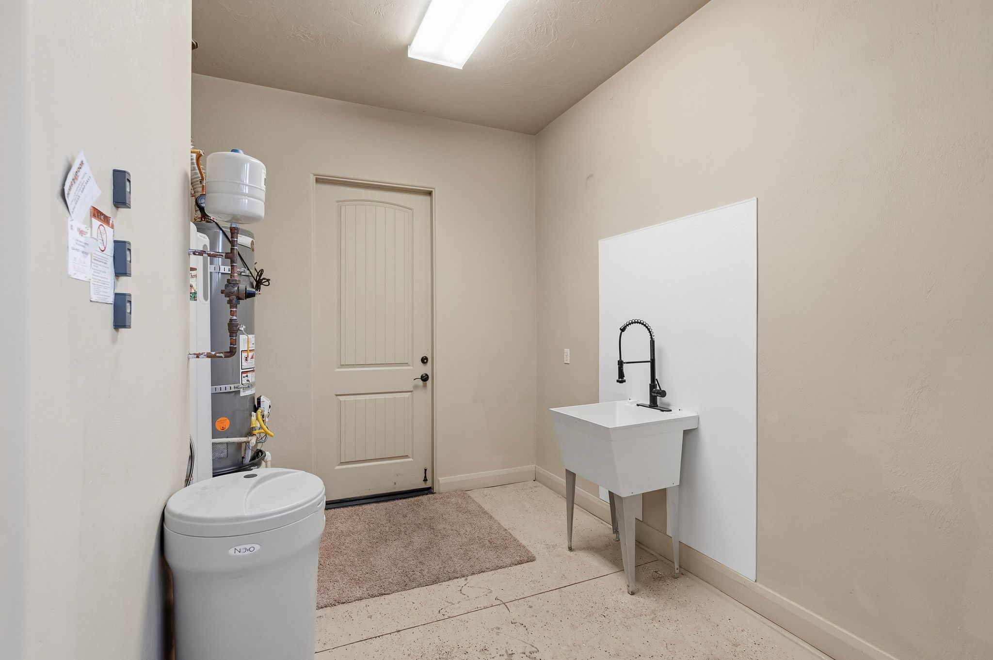 Garage featuring a white sink with a matte black faucet, a paneled door, and a water heater