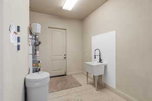 Garage featuring a white sink with a matte black faucet, a paneled door, and a water heater
