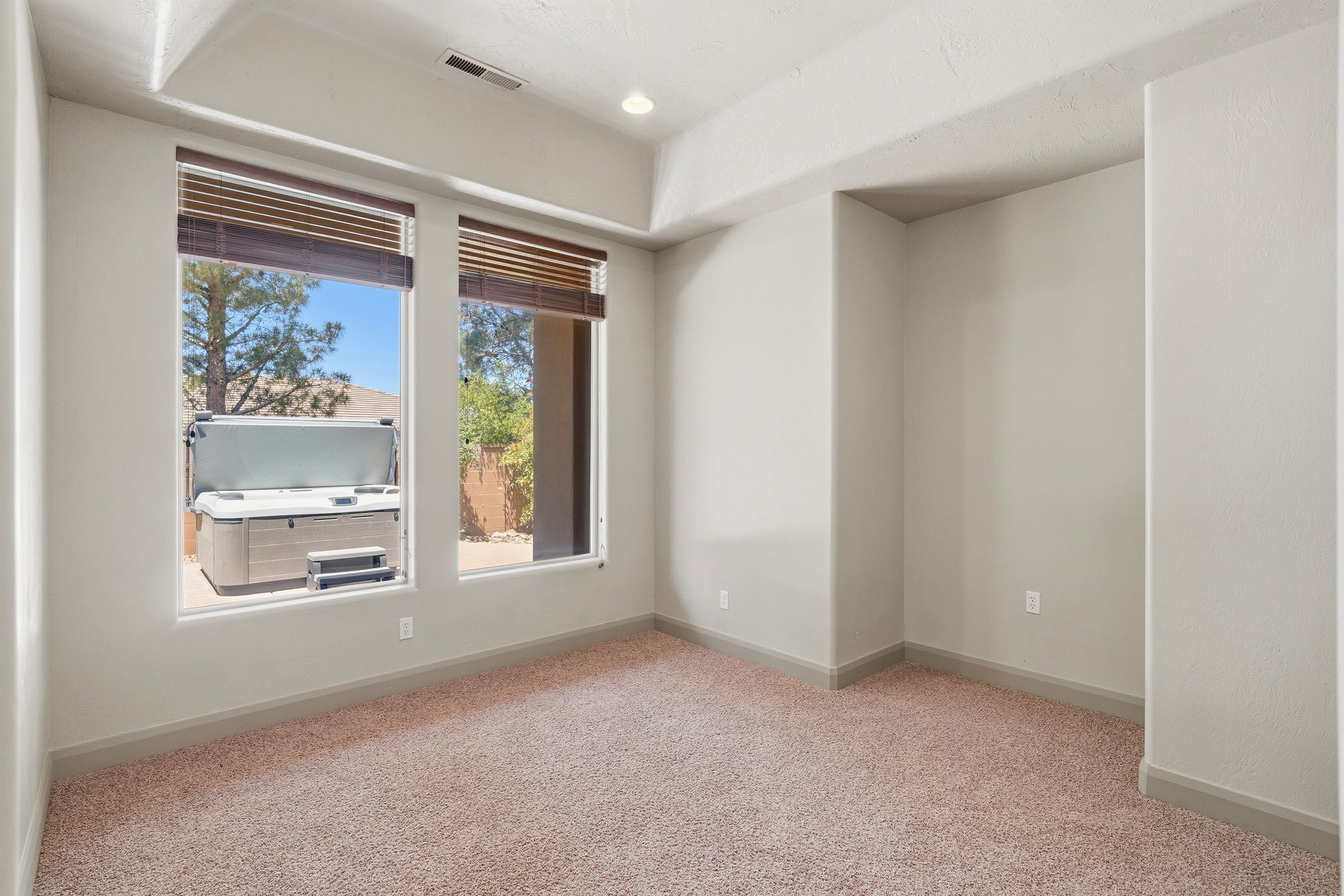 Primary suite, extra room within primary suite. Featuring dual windows with woven wood blinds and recessed lighting.