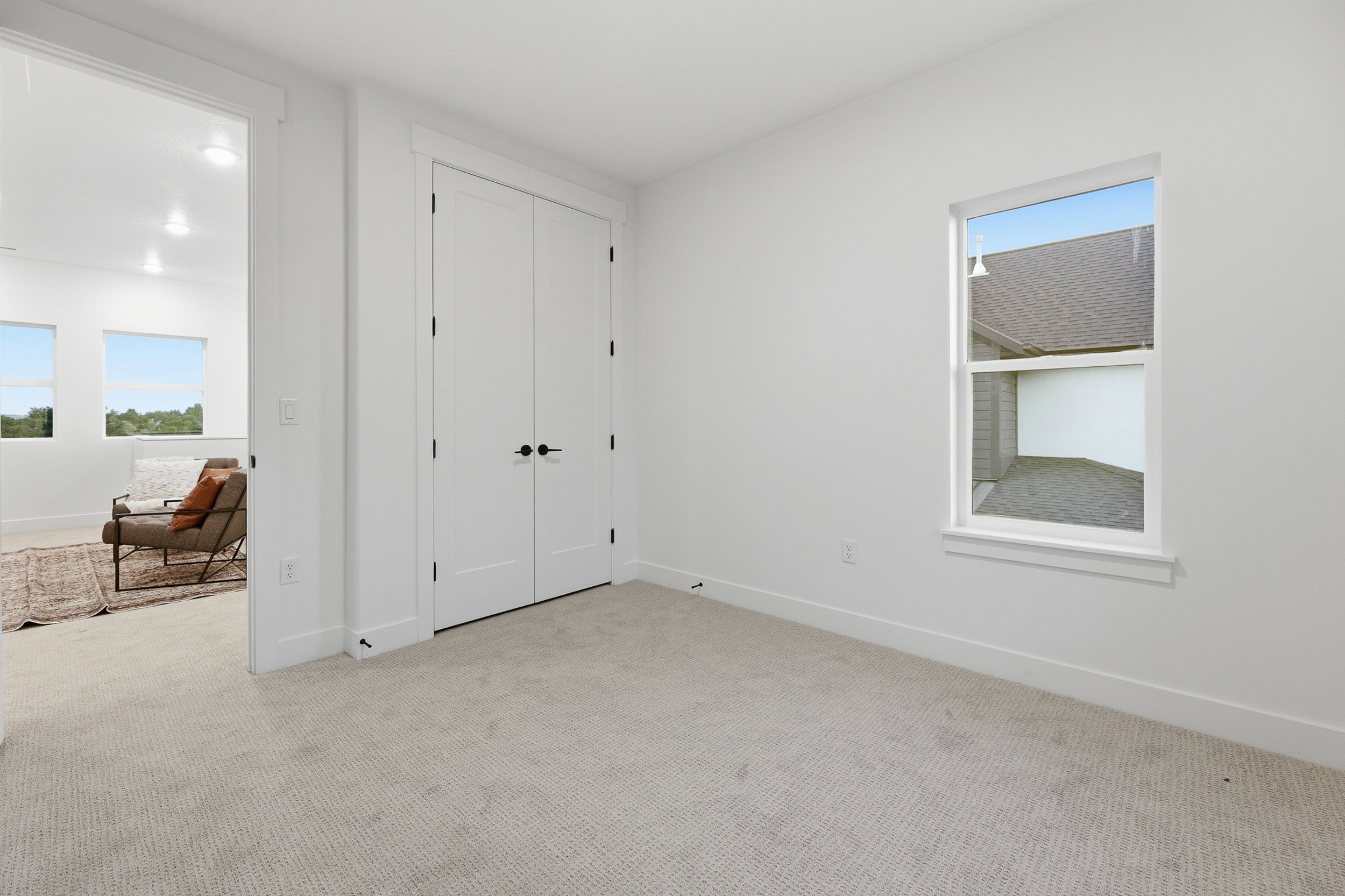 Carpeted room featuring a double-door closet, a single window, and a doorway opening to another room