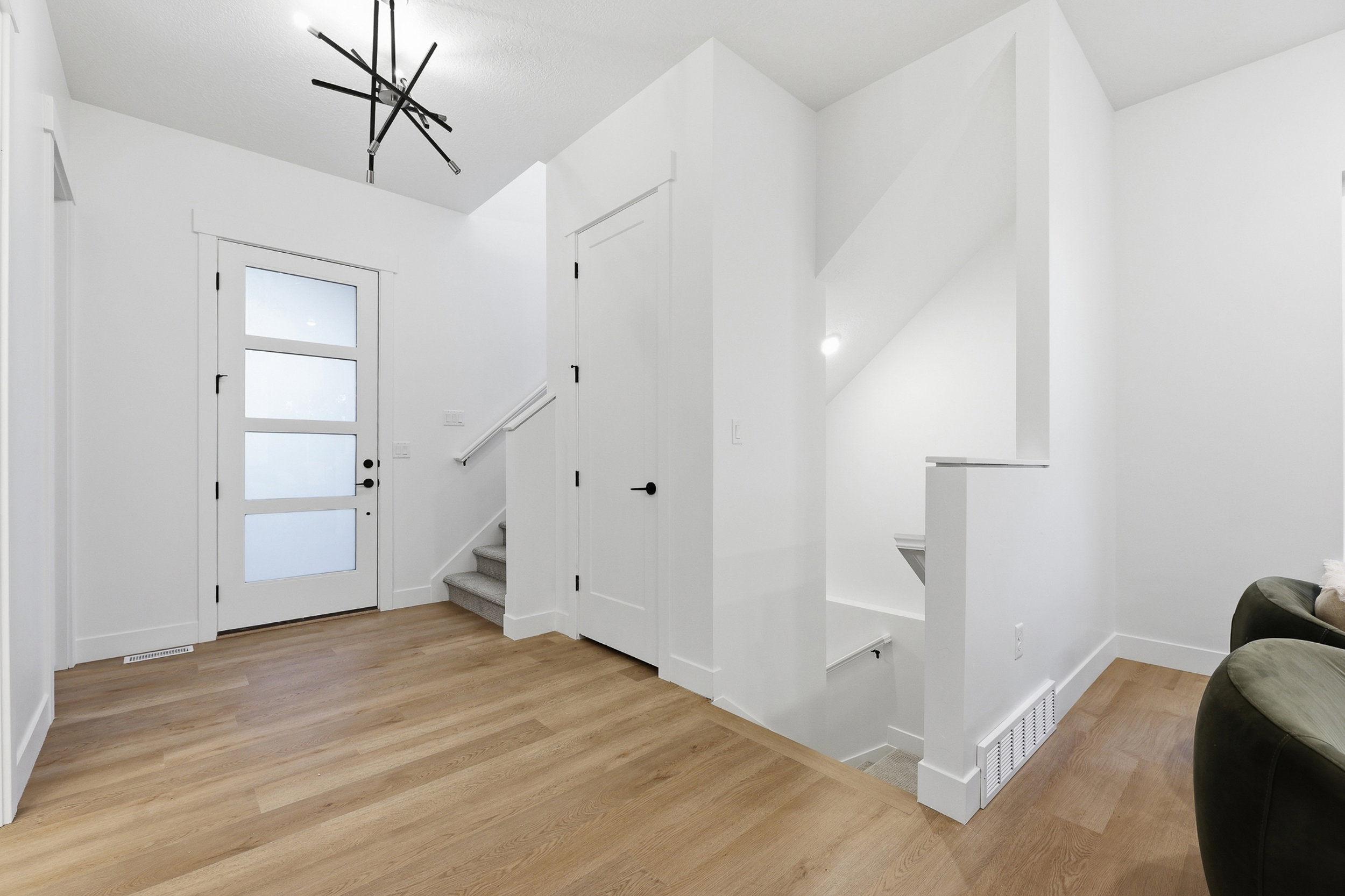 Entryway with wood-finish flooring, a modern front door with frosted glass panels, and a contemporary linear chandelier