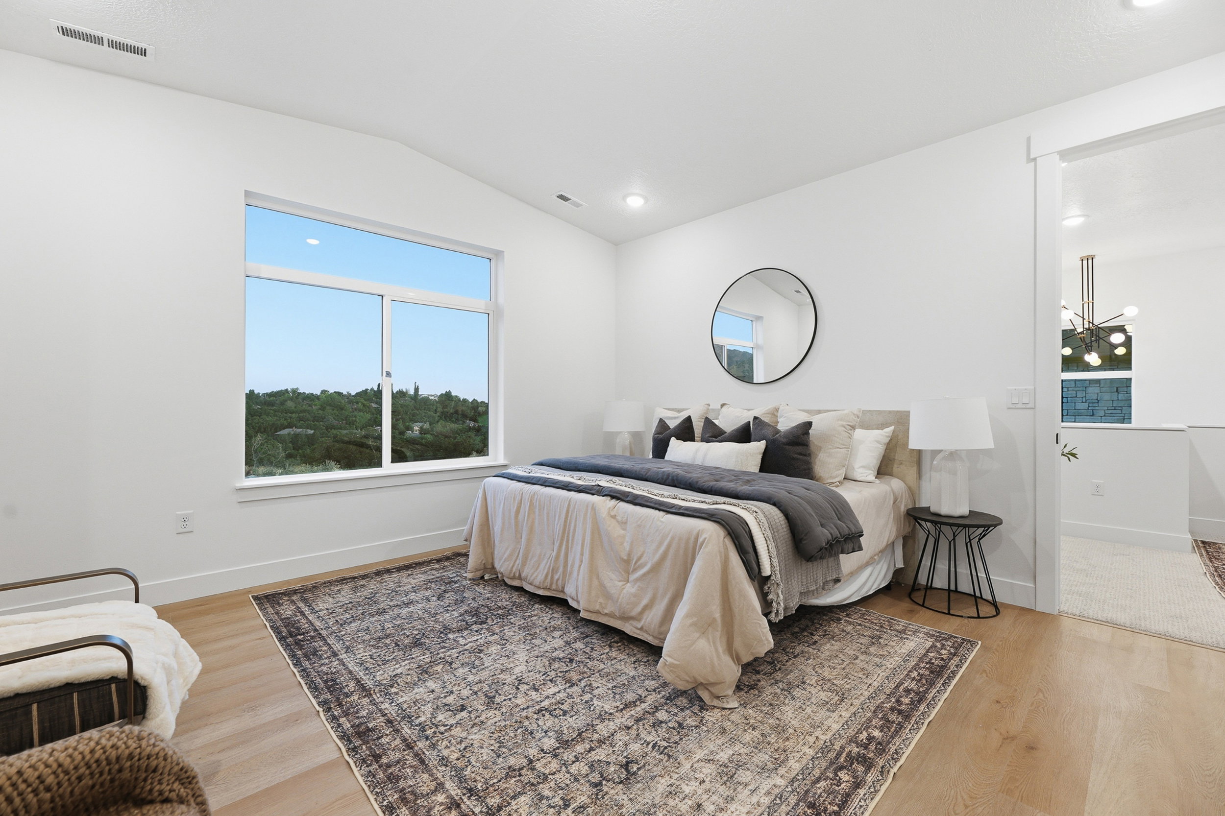 Spacious bedroom featuring light wood-finish flooring, a large picture window, vaulted ceilings, recessed lighting, and crisp white walls