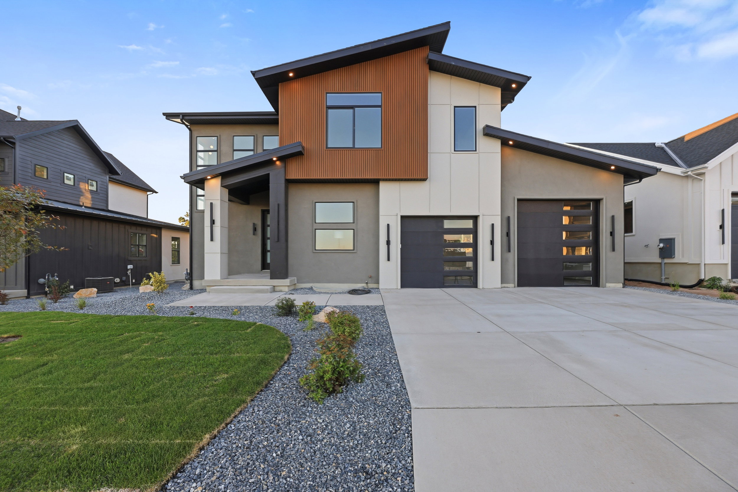 Contemporary architectural facade featuring a prominent wood-finish accent panel, dark gray stucco, and white paneling