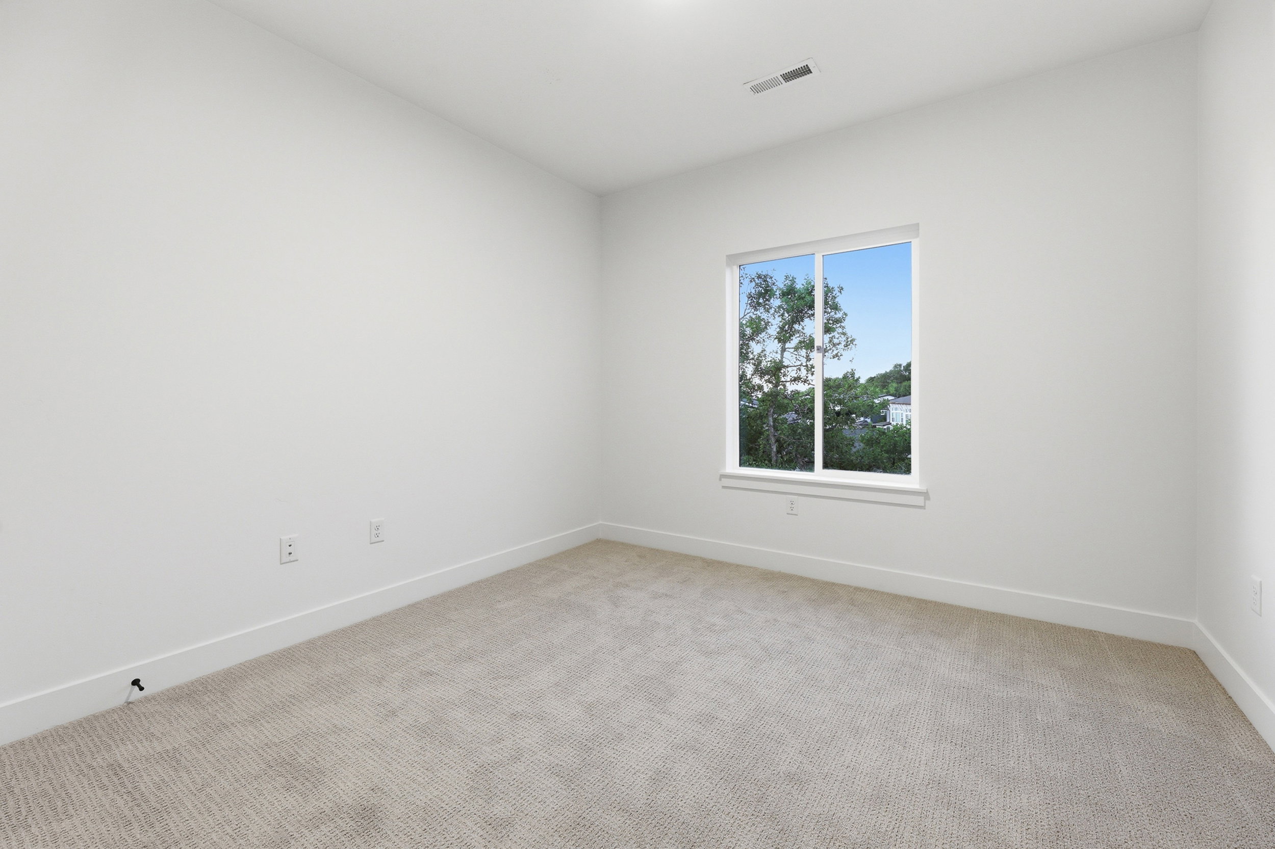 Neutral-toned carpeted room featuring a single window and crisp white walls