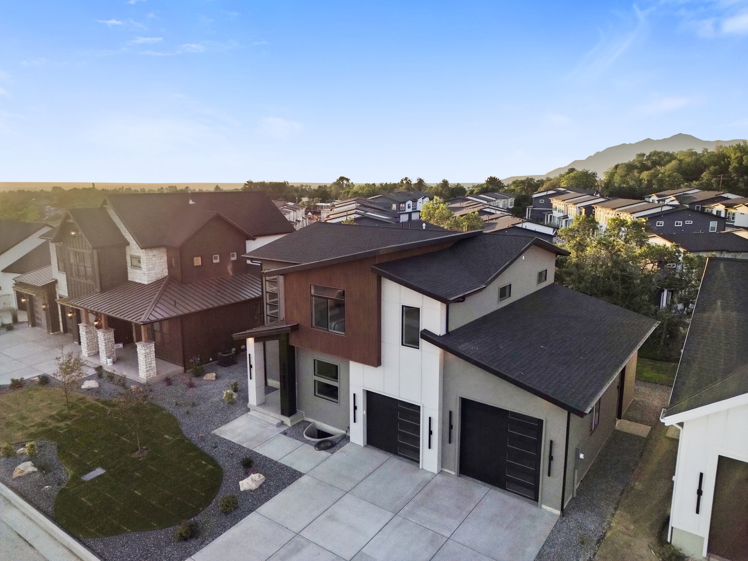 Contemporary multi-level residence featuring a dark asphalt shingle roof, two distinct garage doors with frosted panels, and a concrete driveway