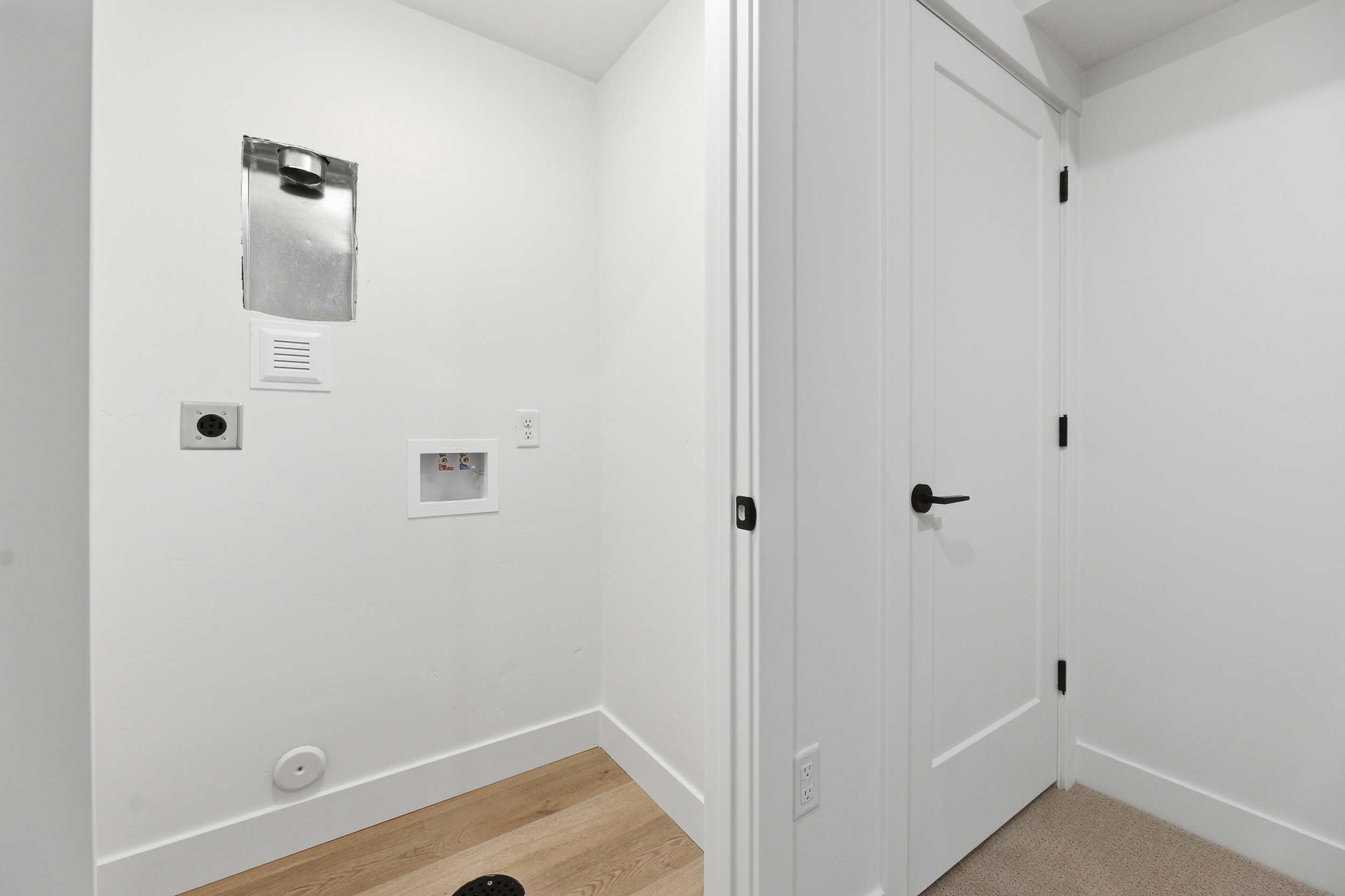 Dedicated laundry area featuring a dryer vent, utility hookups, and wood-finish flooring