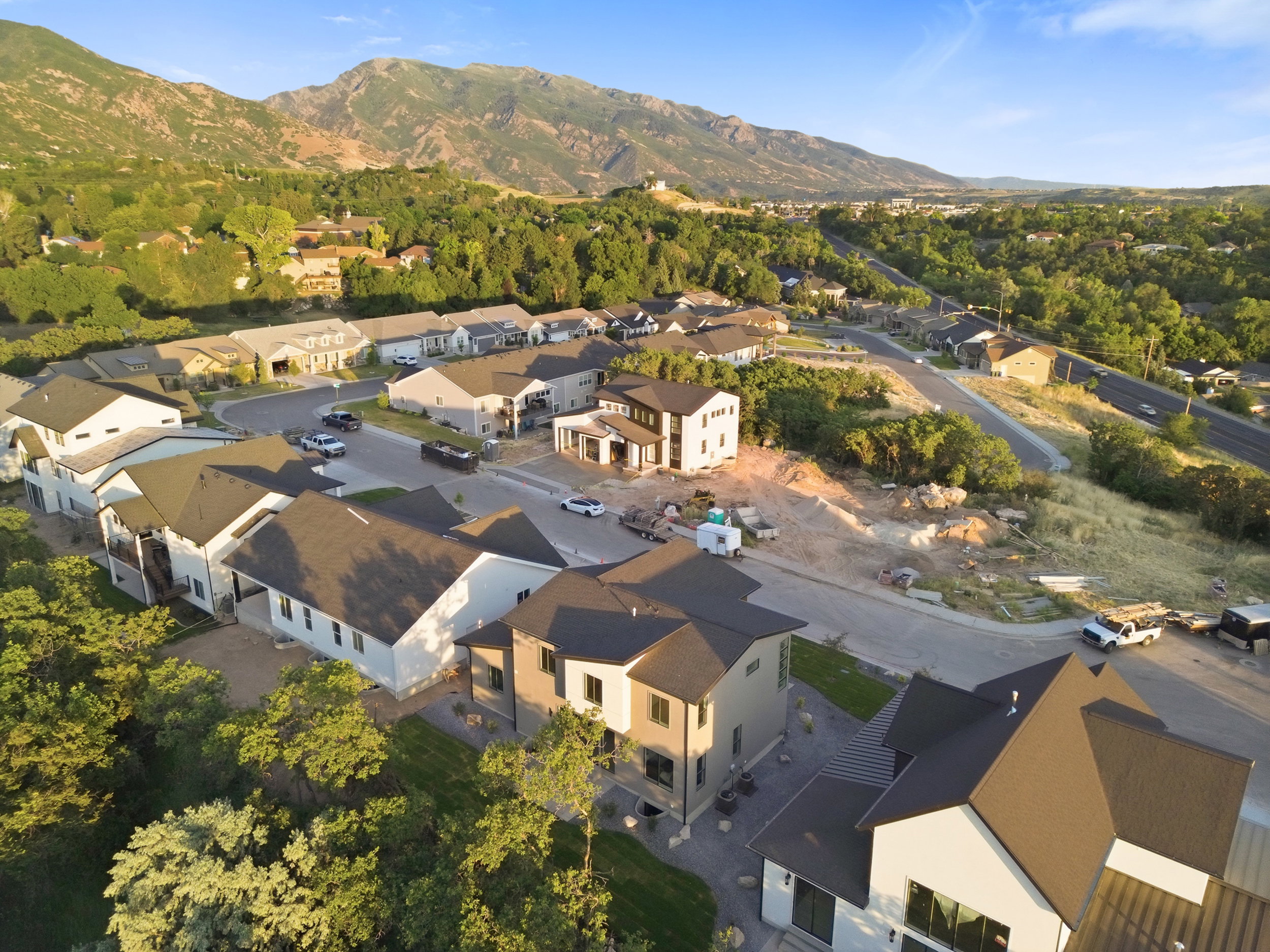 Contemporary residential architecture with dark pitched roofs and light-toned exteriors, set against a mountainous backdrop