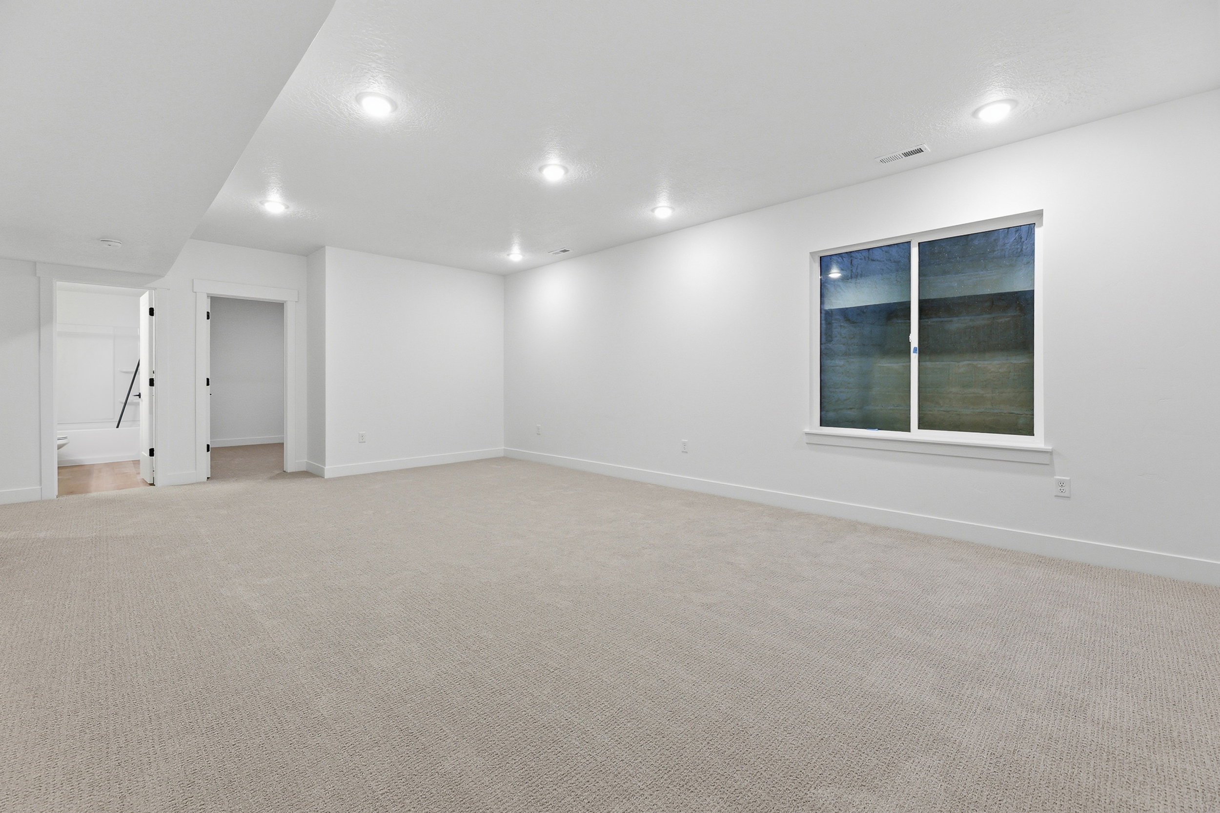 Expansive room featuring light-colored carpeting, white walls, and recessed lighting