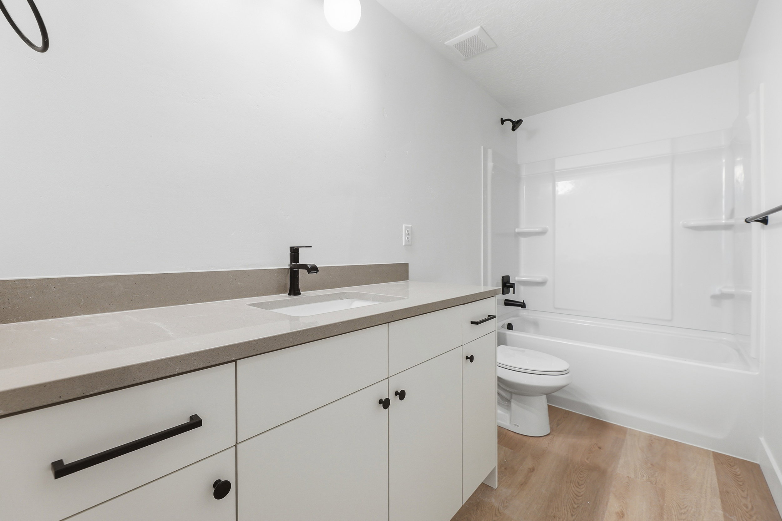 Bathroom featuring a white vanity with a light-toned countertop, an integrated sink, and matte black fixtures