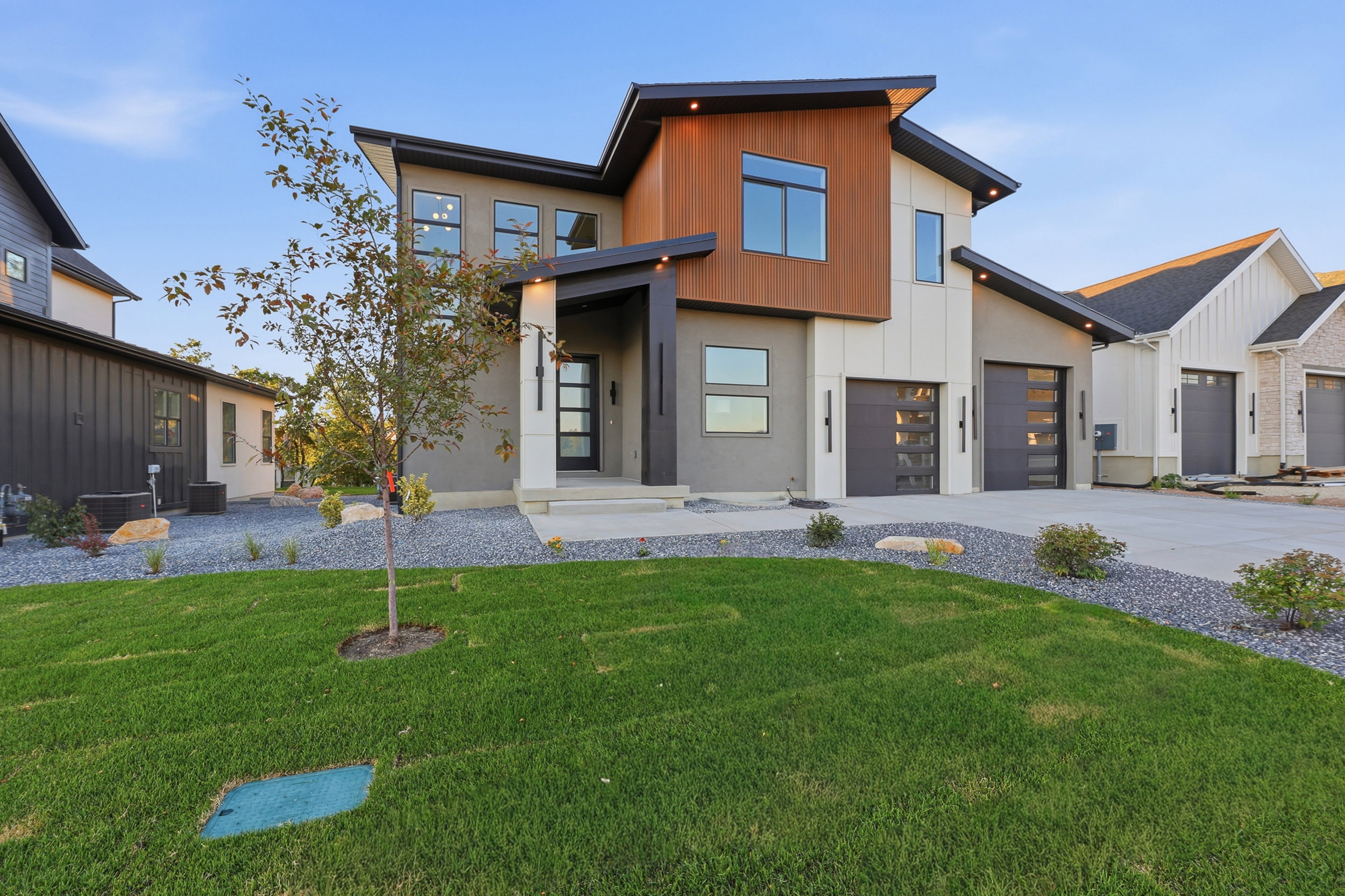 Contemporary architectural design featuring a multi-textured facade with wood-finish siding, white vertical siding, and stucco