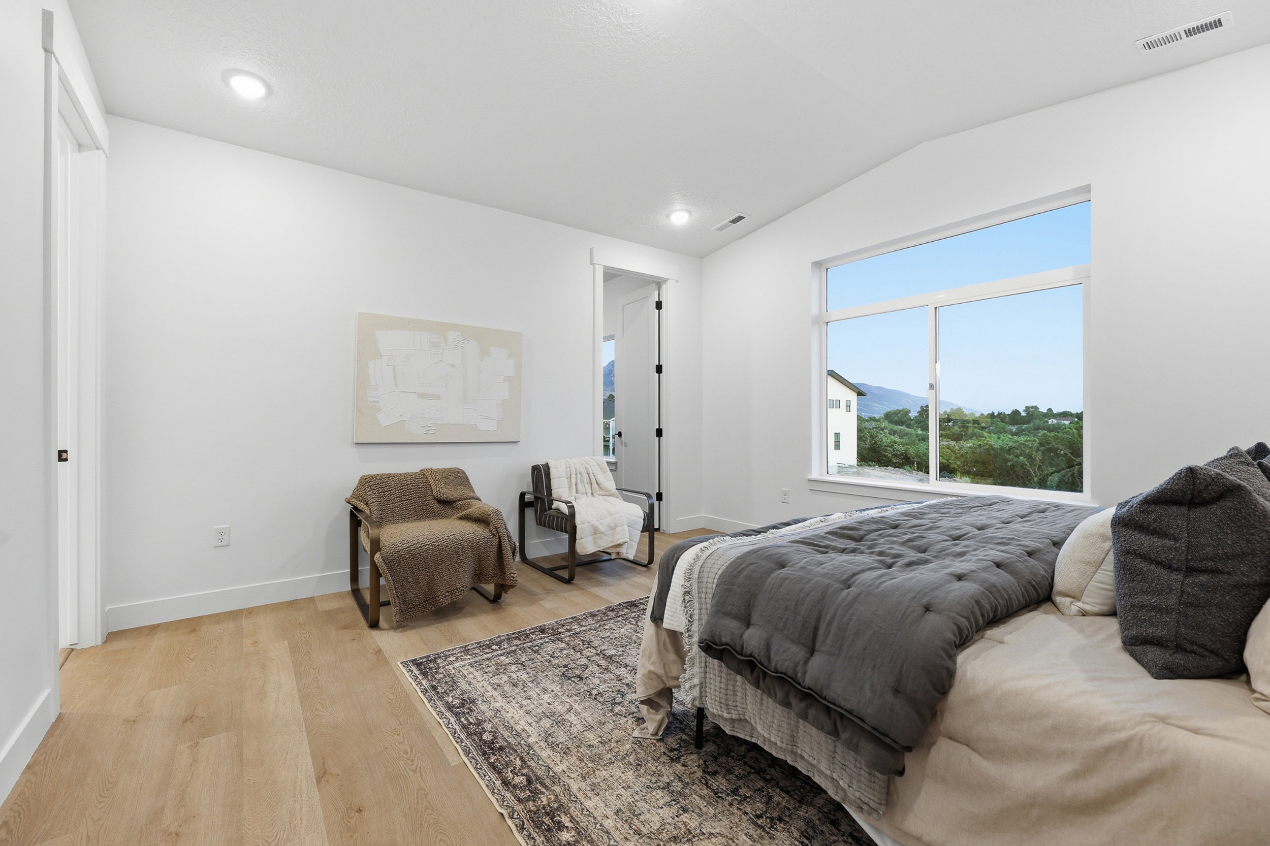 Spacious room featuring light wood-finish flooring, recessed lighting, and a vaulted ceiling