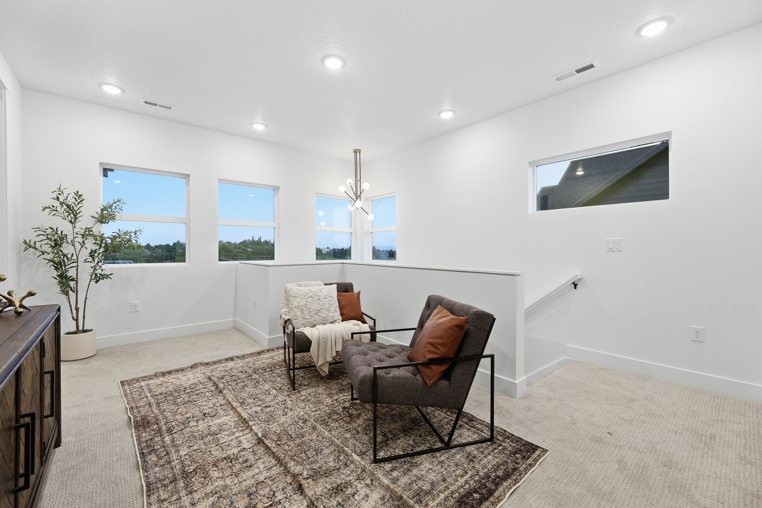 Bright upper-level bonus room featuring recessed lighting, multiple windows, carpet flooring, a contemporary chandelier, and a half-wall overlooking a lower level