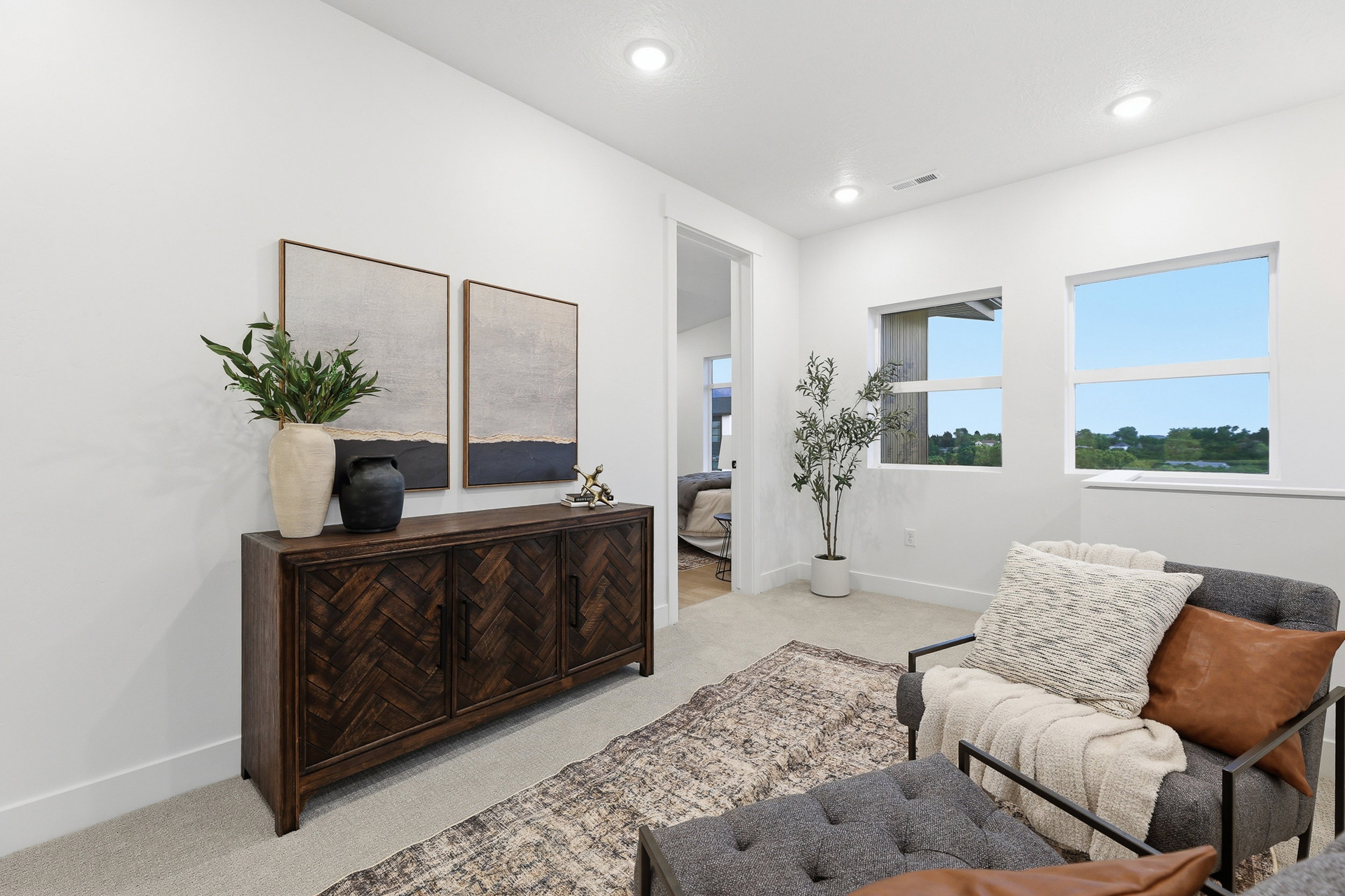 Bright room featuring recessed lighting, two windows with clear glass, light-colored carpeting, and a dark wood-finish cabinet with textured doors