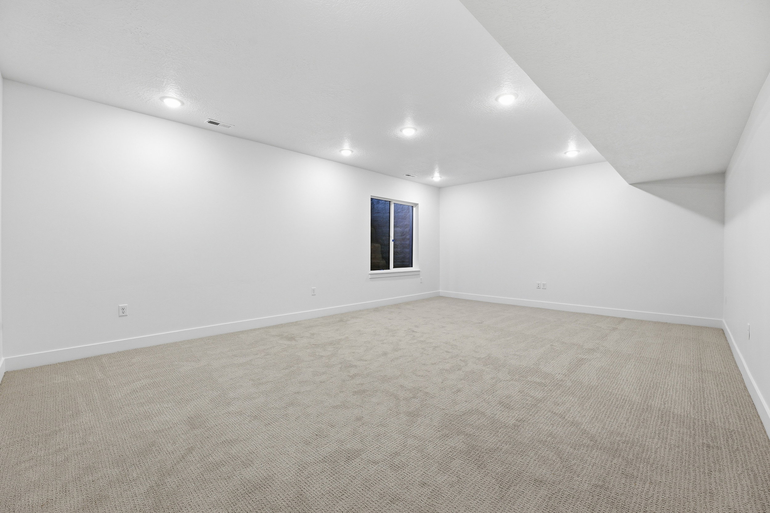 Spacious room featuring light-colored carpeting, white baseboards, and neutral wall paint