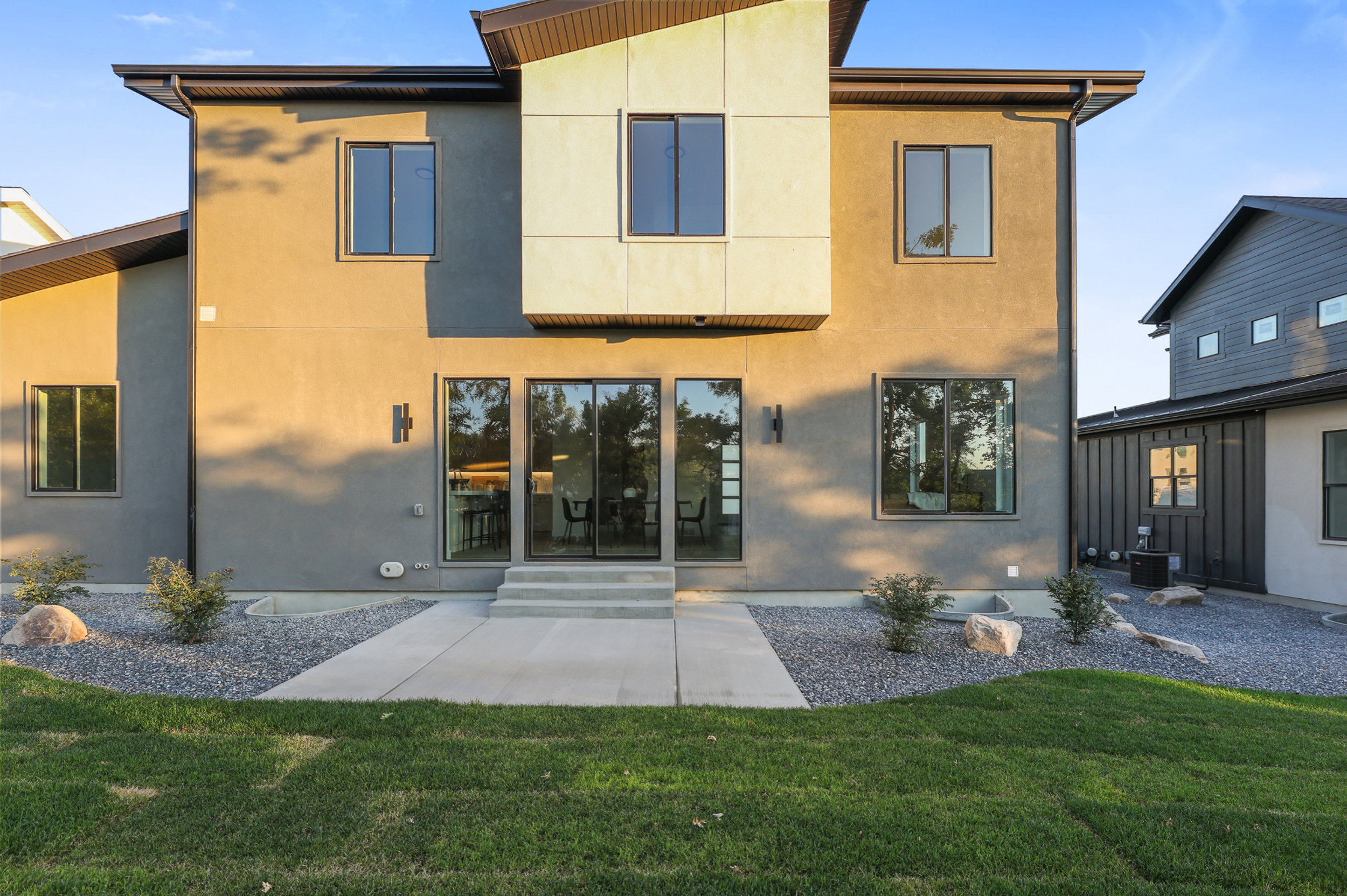 Contemporary rear exterior featuring stucco siding and contrasting modern paneling