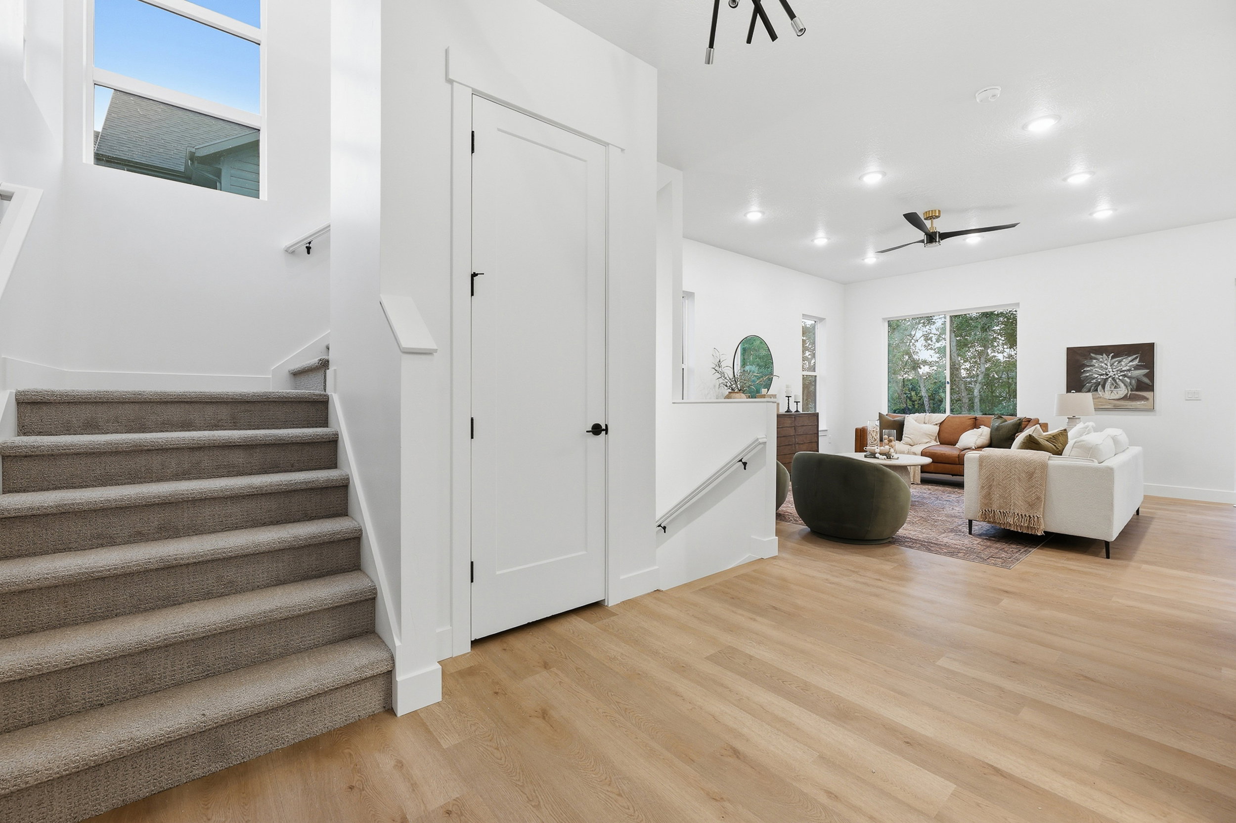 Open concept living area with light wood-finish flooring, recessed lighting, and a modern ceiling fan