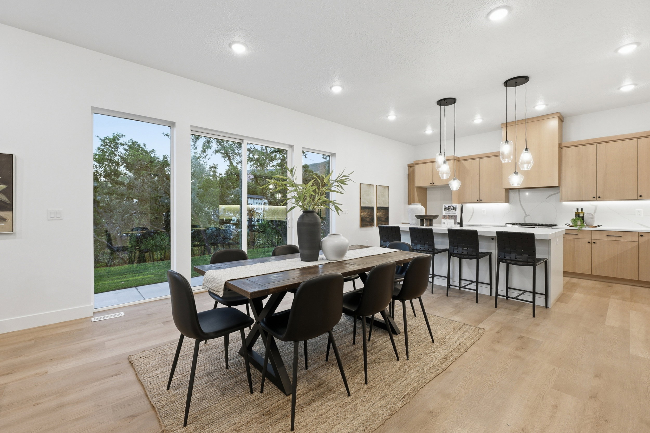 Expansive dining area with light wood-finish flooring, recessed lighting, and large windows