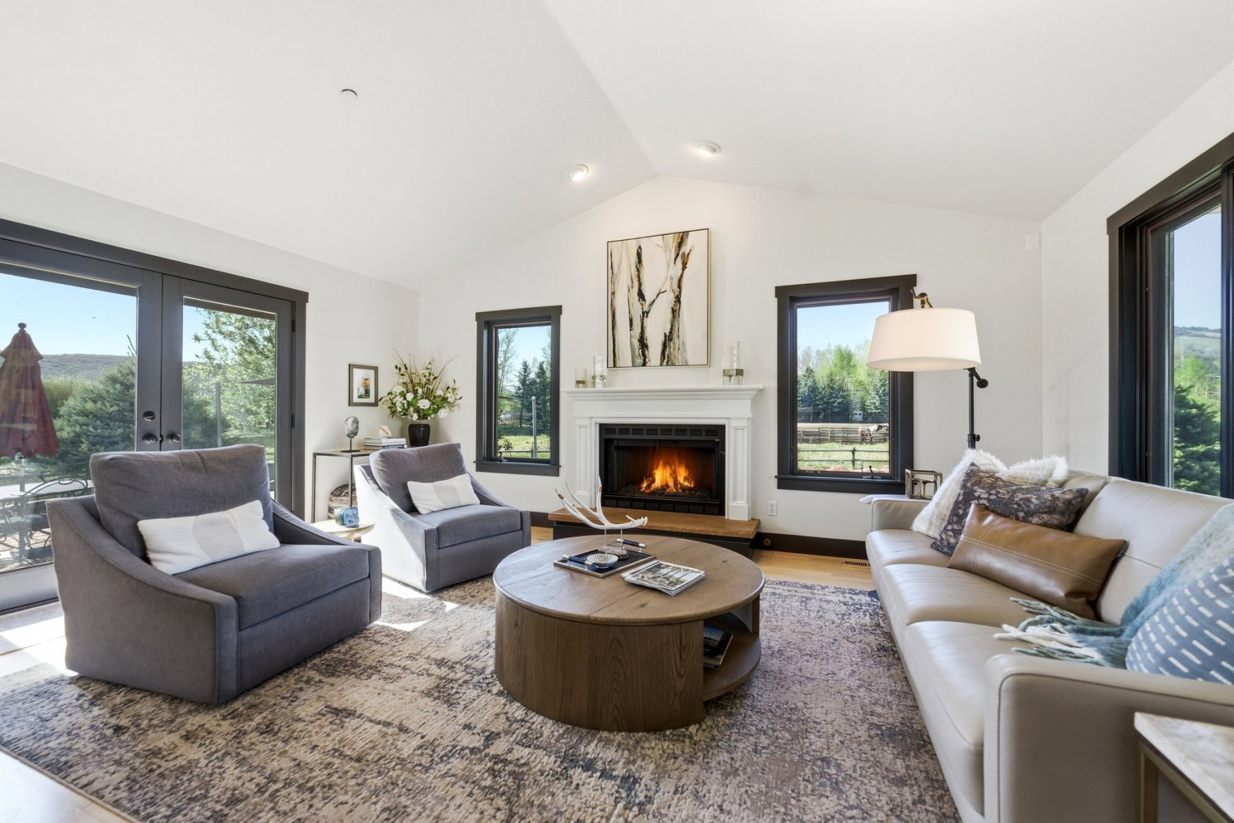 Living area featuring a vaulted ceiling and a fireplace with a white mantel and wood surround
