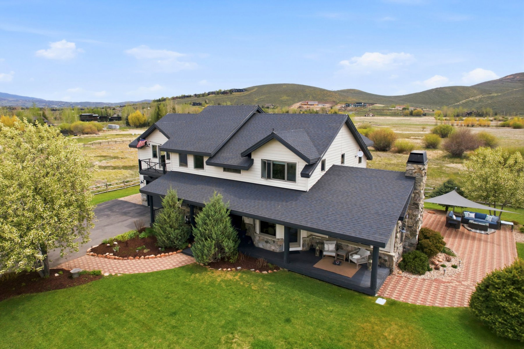 Two-story home featuring light-colored siding, a dark roof, and stone accents