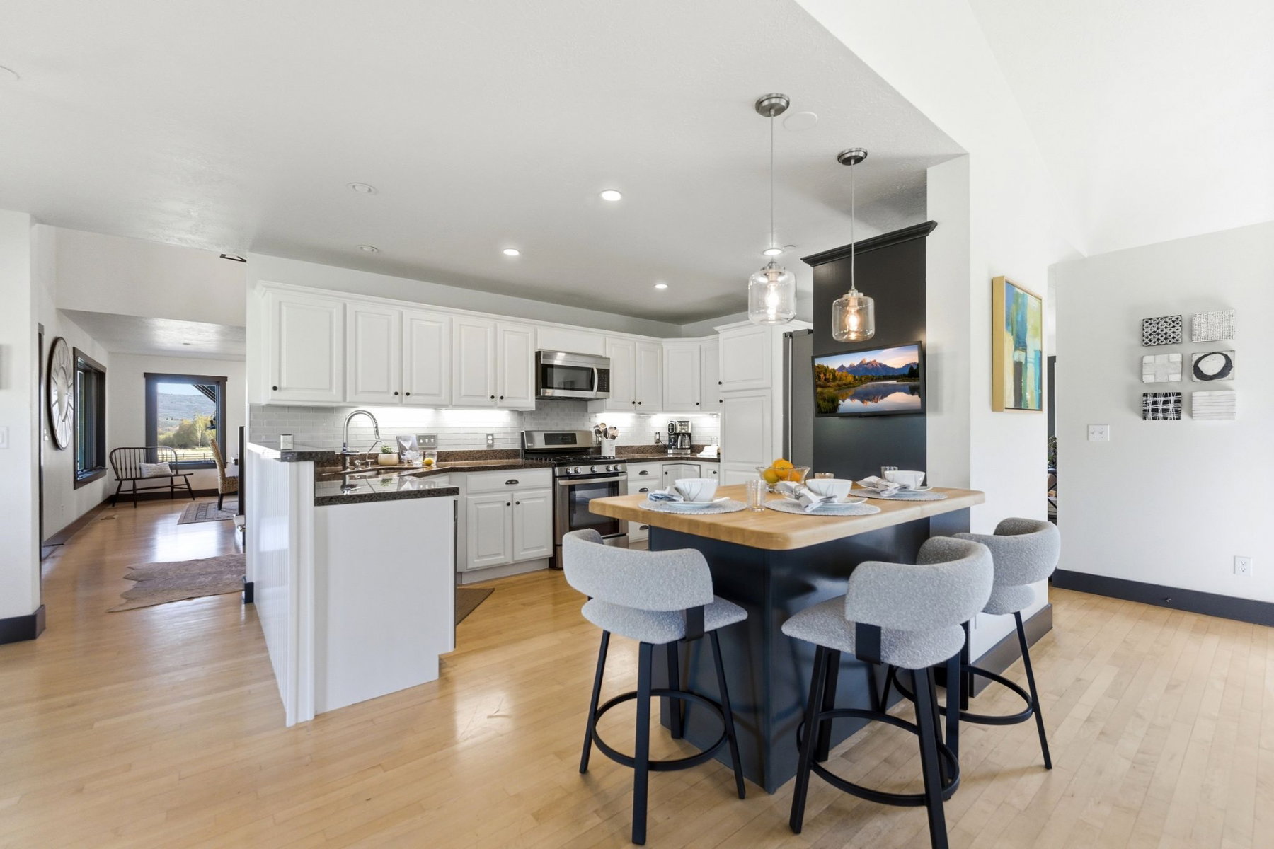 Kitchen featuring white cabinetry, stainless steel appliances, dark countertops, and a central island with wood-finish countertop