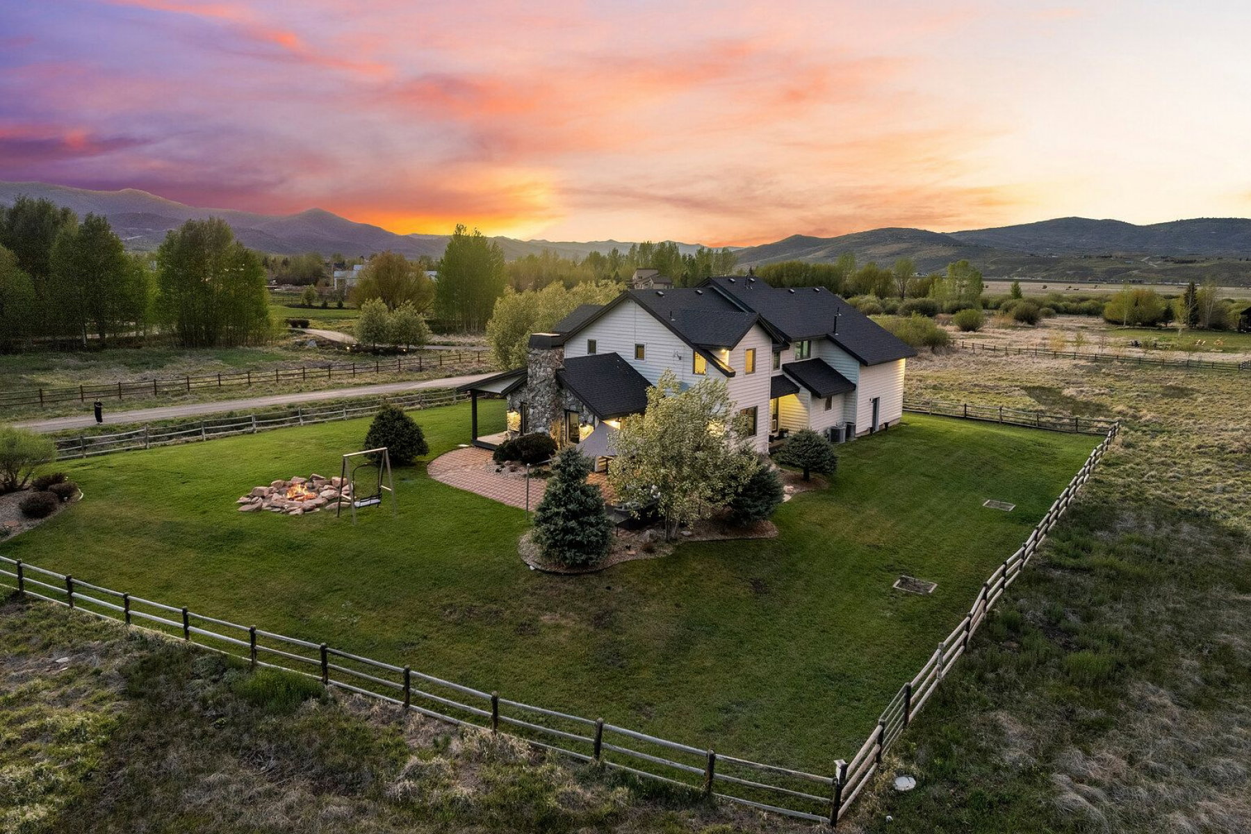 Expansive property featuring a stone-clad exterior, a large manicured lawn, and a paved patio area