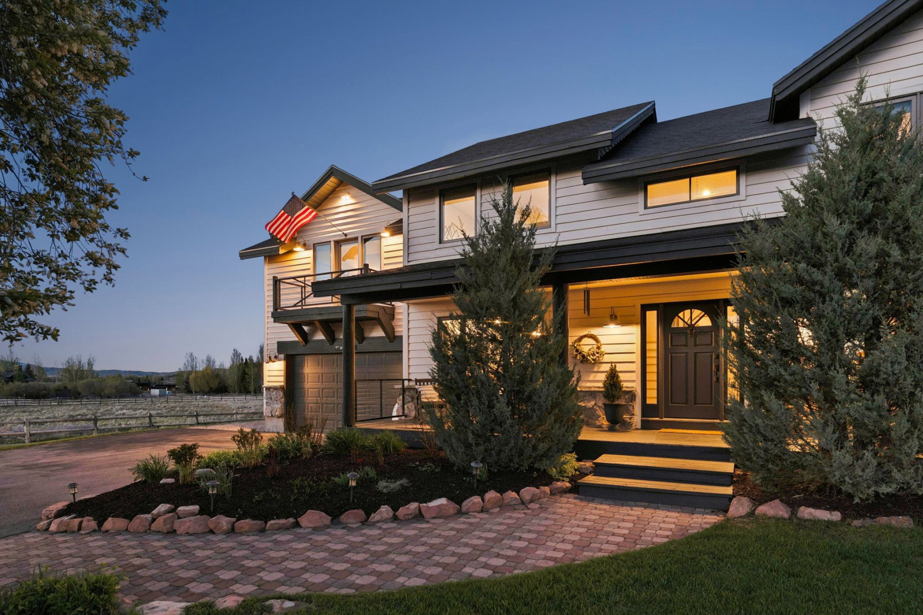 Two-story residence featuring light-colored siding with dark trim, a covered front porch, and an attached garage
